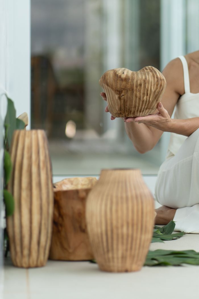 services-img Beautiful handcrafted wooden vases with artistic design held by a woman in a modern indoor setting.