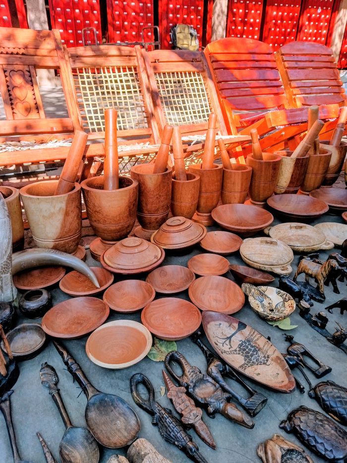 services-03 A vibrant collection of handcrafted wooden kitchen utensils and art pieces on display outdoors.